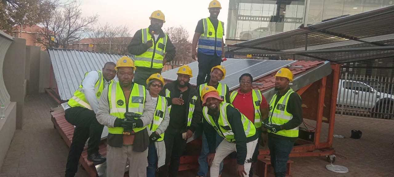 Group of trainees in hard hats and safety vests in front of the training rig