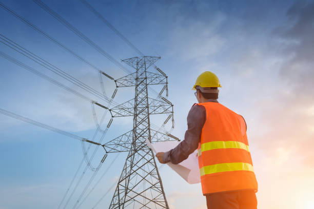Engineering working on high-voltage tower,Check the information on paper at sunset background